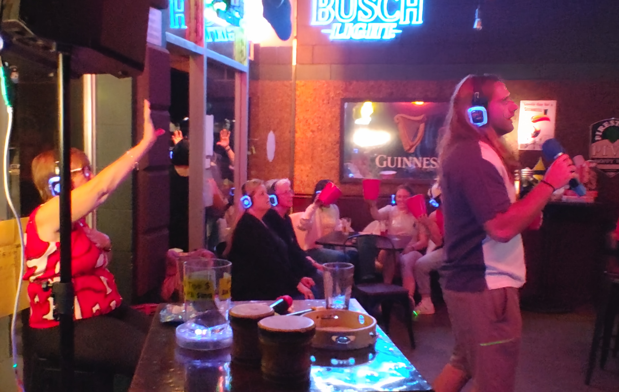 Silent karaoke guests wearing illuminated wireless headphones